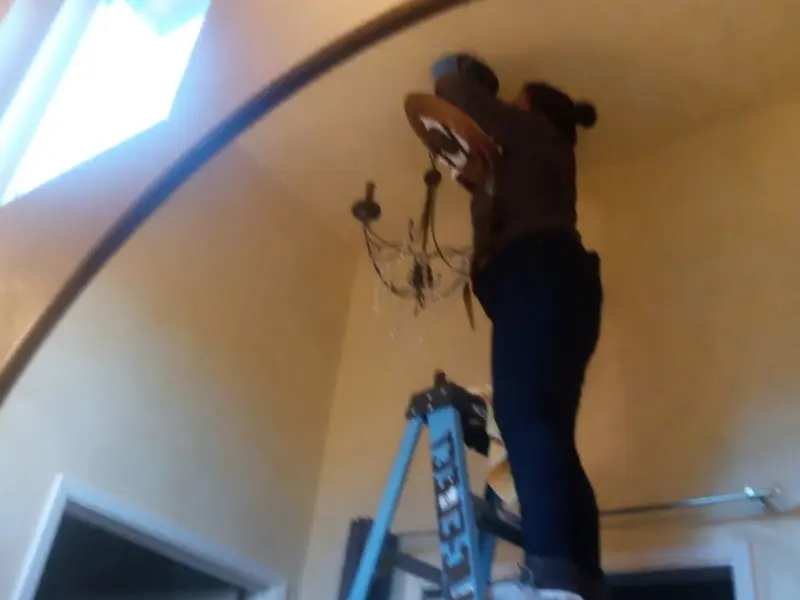 Electrician installing a chandelier in a South Hill residence